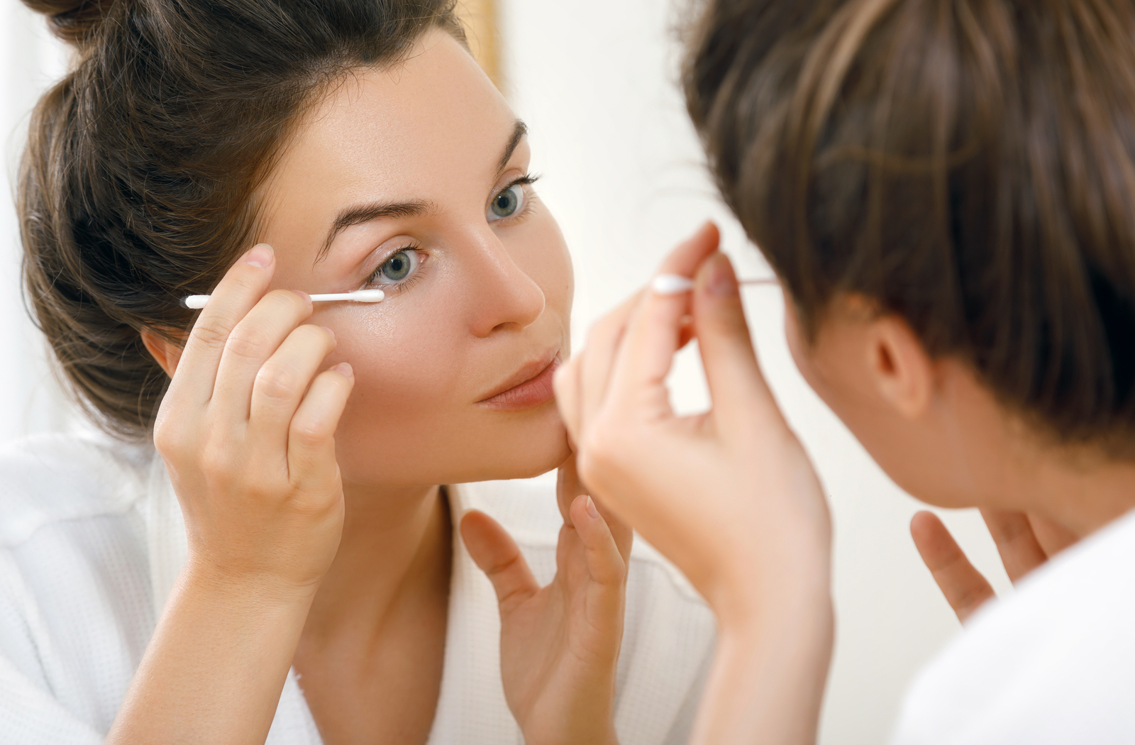 Women cleaning eyelid in front of mirror using beauty tools to improve dry eyes