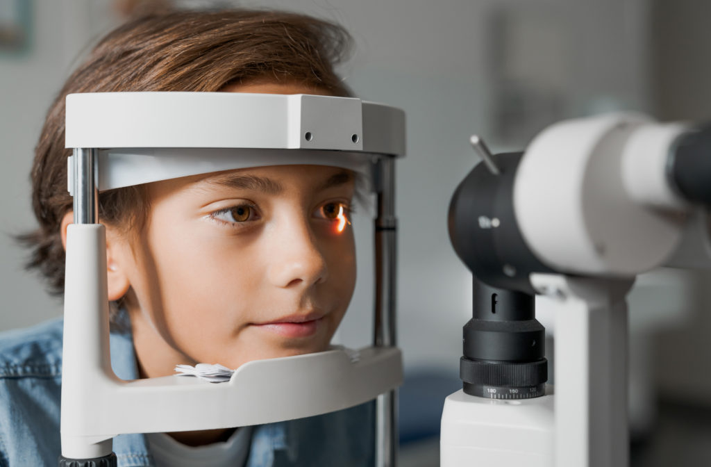 Young boy with chin on eye exam machine ready to have his eye checked out