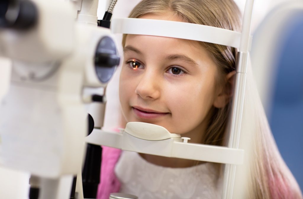 Young girl undergoing eye exam with light shinning at her eye