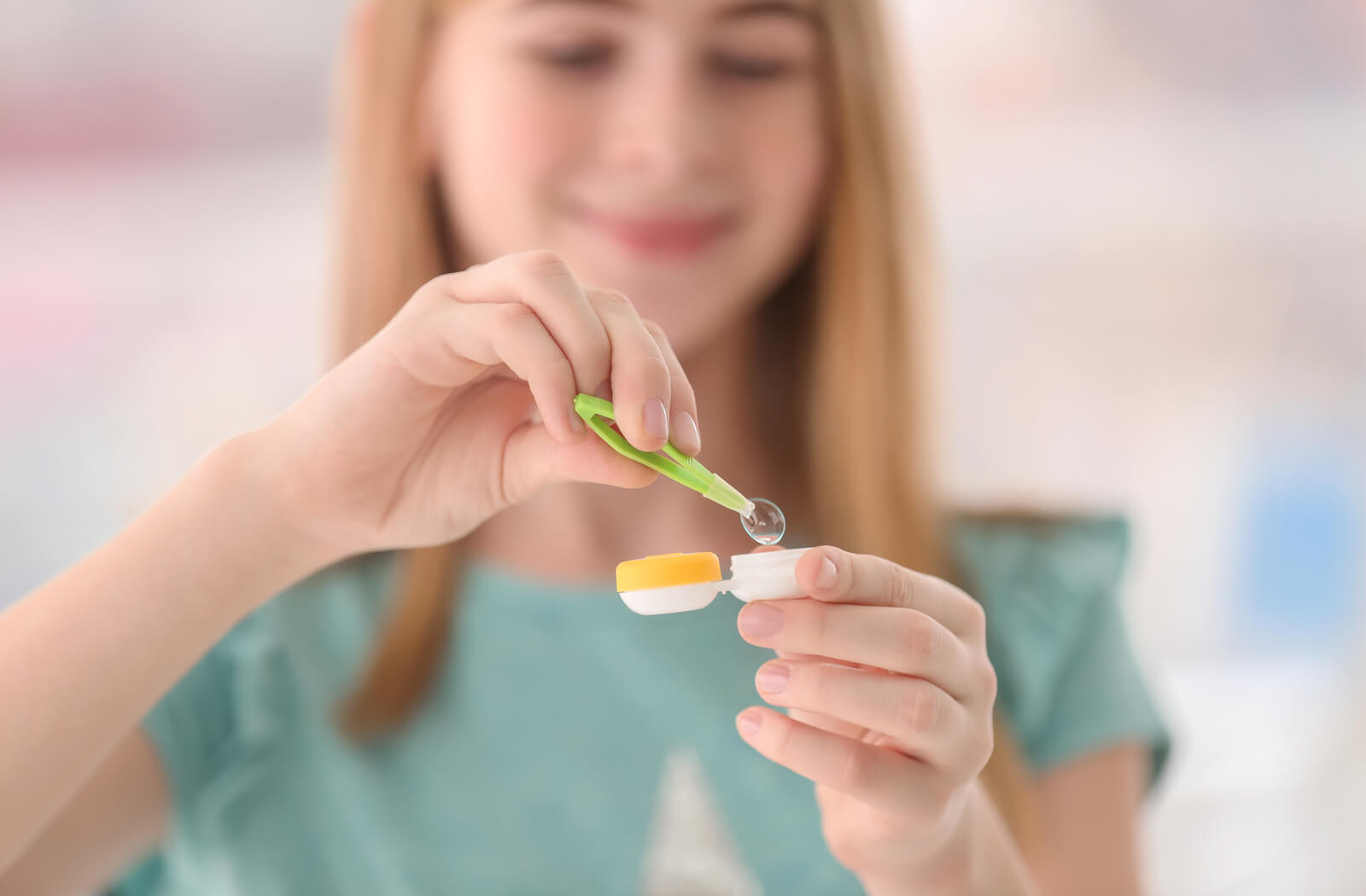 a teenage girl holds a contact lens case that is holding her myopia control lenses
