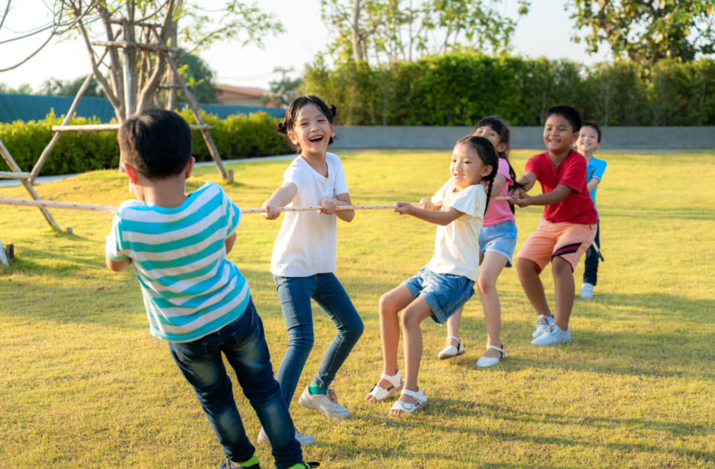 A group of kids playing tug of war outdoors.