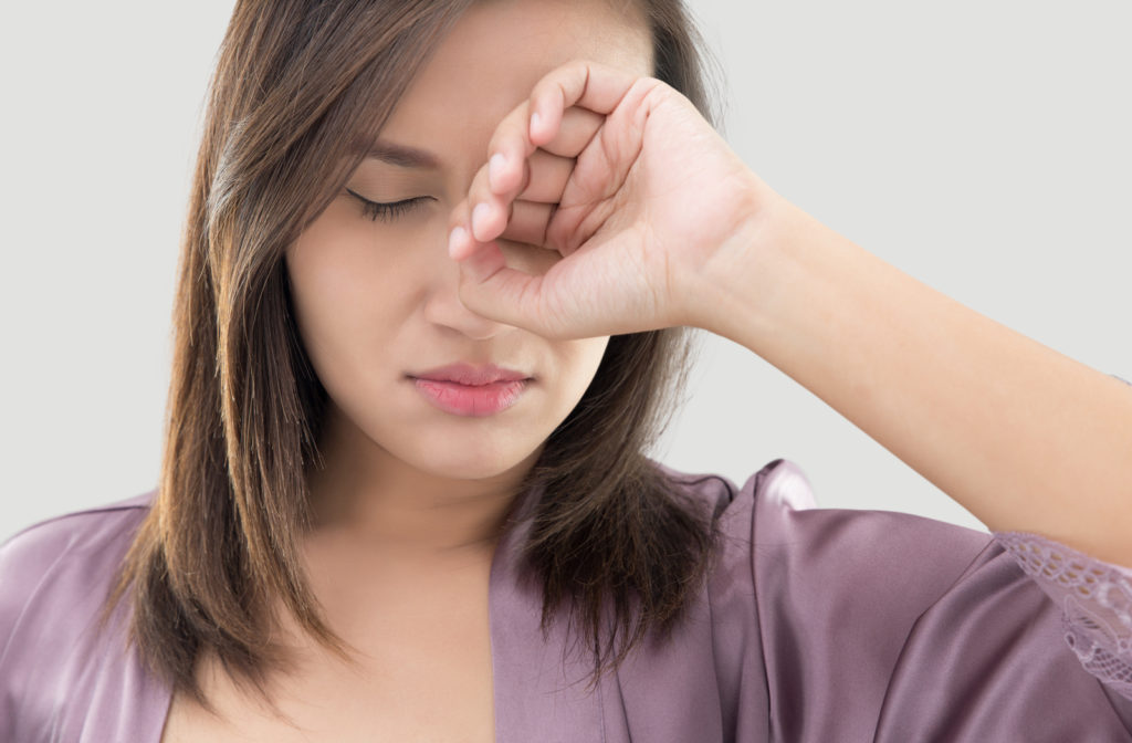 A woman in purple robes is rubbing her itching dry eyes.