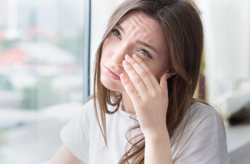 "A young woman is experiencing burning and stinging in her eyes due to dry eyes."