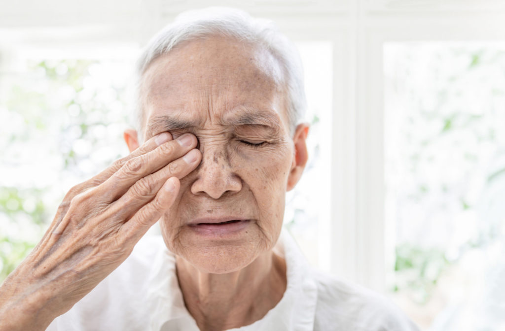 A senior woman with eyes close, rubbing her right eyes with her right hand.