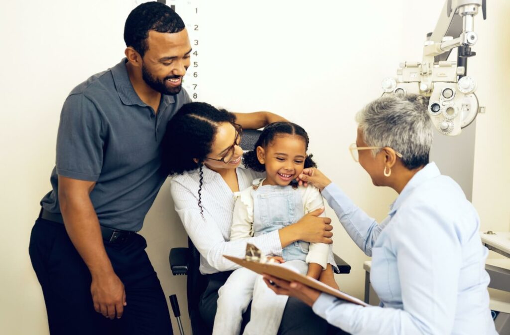 An optometrist explains the importance of vision therapy to the parents of a young girl during her routine eye exam.