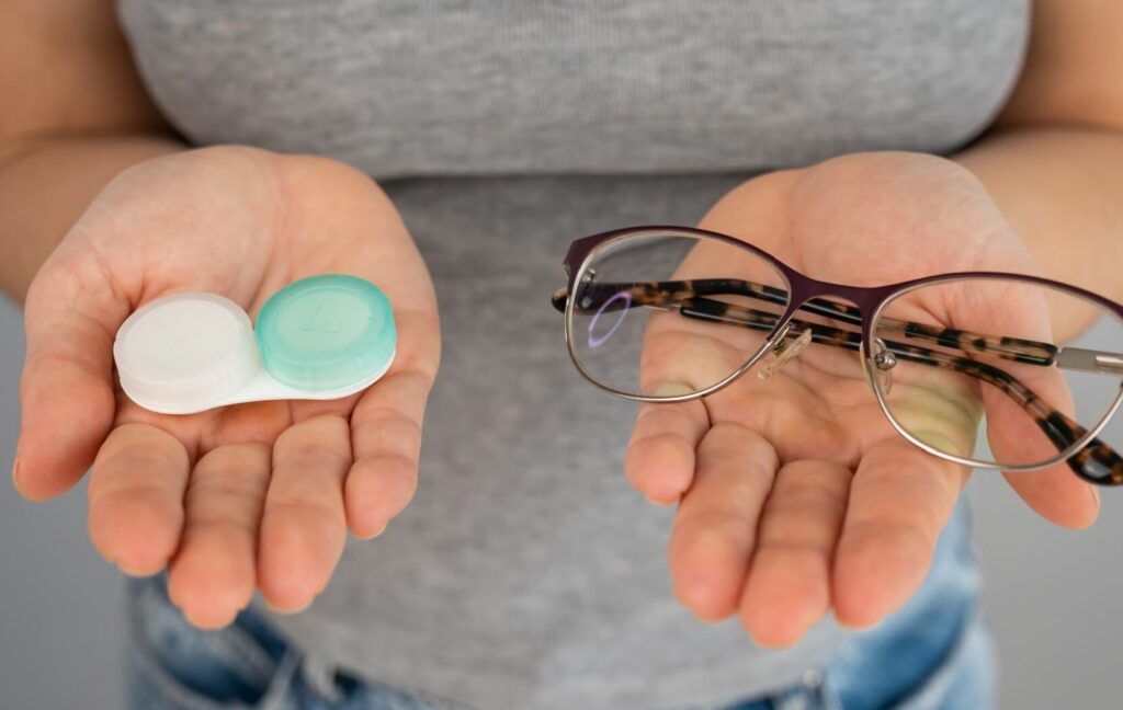 A person deciding on a myopia treatment holds a contacts case in one hand and a pair of eyeglasses in the other hand.