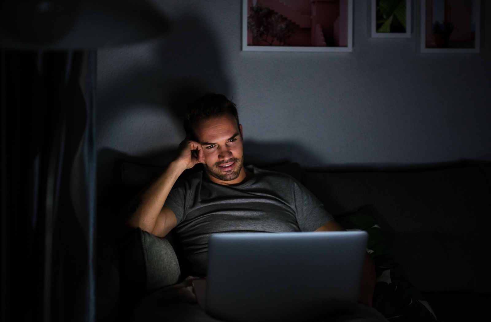 An adult using their computer at night while sitting on the couch in the dark increases the risk of eye strain.