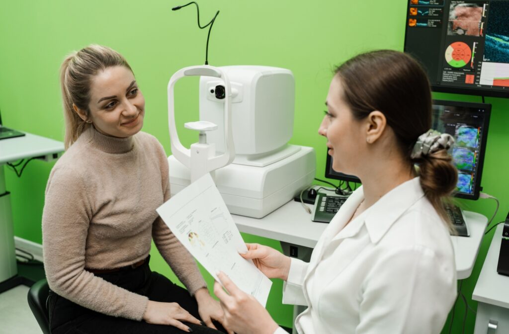 An optometrist holding a piece of paper explains the results of an OCT eye scan to a patient.