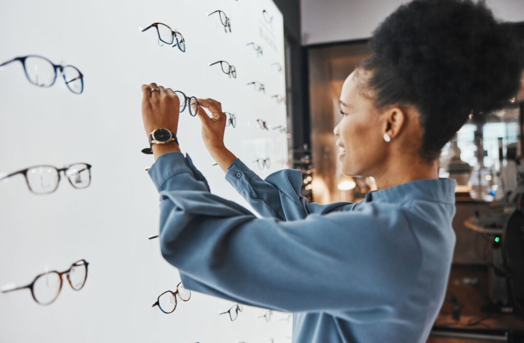 A woman selecting a pair of glasses from a display case.