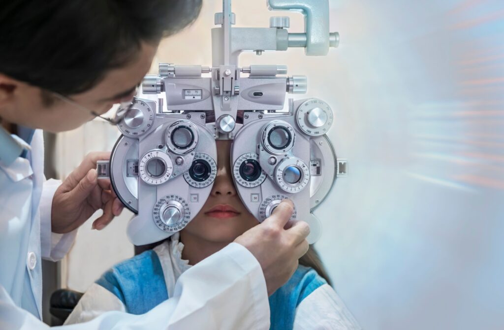 An optometrist adjusting a phoropter on a child's face during an eye exam for myopia.