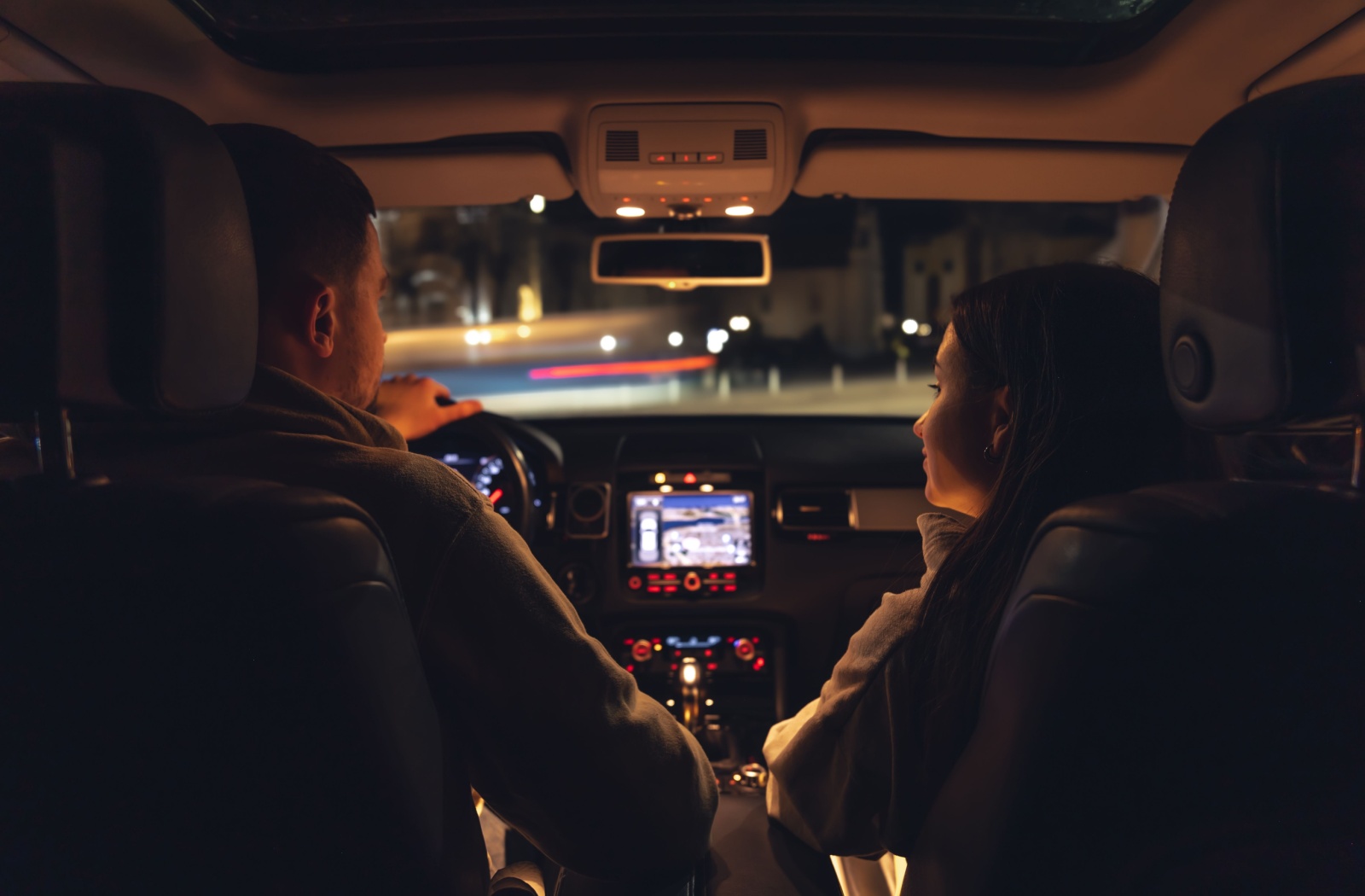 View from the backseat as a couple drives together at night.