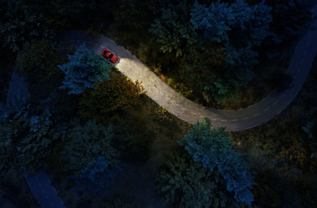 Overhead view of a car driving through a mountain road at night.