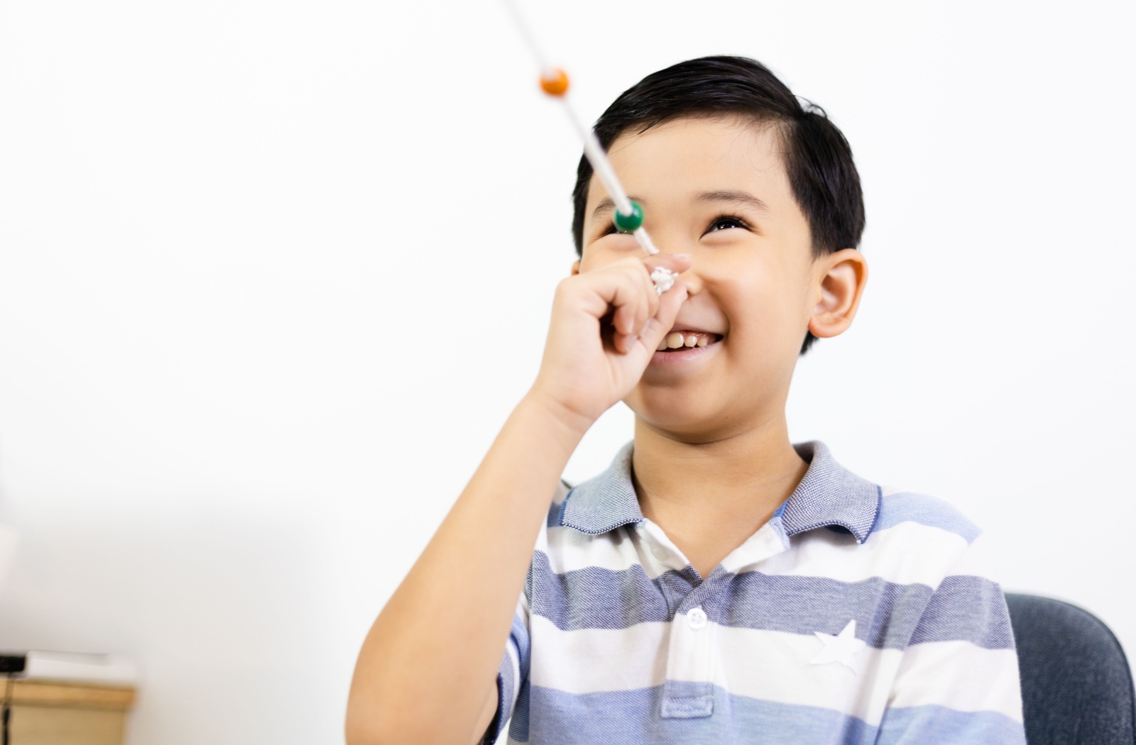Young boy practicing Brock string exercise for vision therapy at Foresee Eyecare.